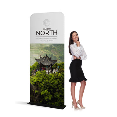 Tall fabric banner stand with travel tour advertisement next to standing woman for trade shows and events