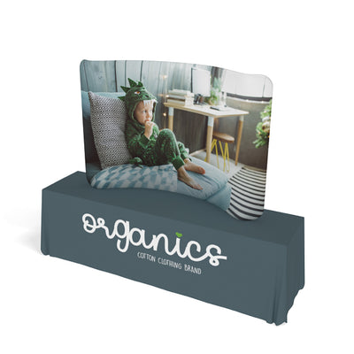 Curved tabletop trade show display with child in dinosaur outfit imagery, branded table cover