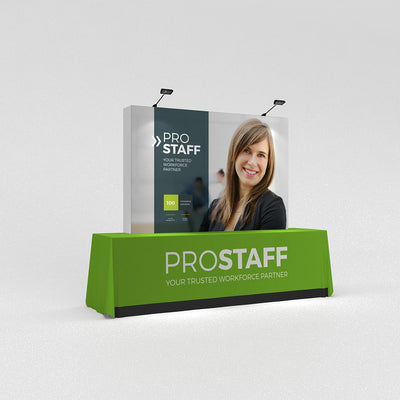 Portable trade show display with branded table cover and backdrop featuring a staff portrait and company logo