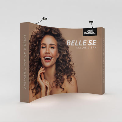 Curved fabric pop-up display for trade shows featuring salon and spa branding with smiling woman